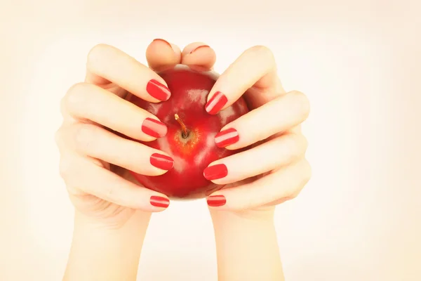 Rote Nägel Maniküre Hand mit Apfel — Stockfoto