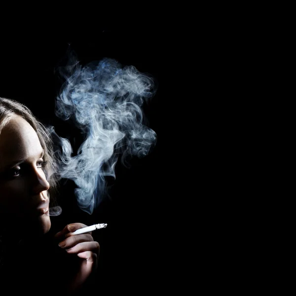 Курящая женщина в темноте — стоковое фото