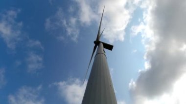 Bıçaklı rüzgar türbini düşük açılı temiz alternatif yenilenebilir enerji üretiyor. Metin ve grafikler için gökyüzü arka planı ve alanı var.