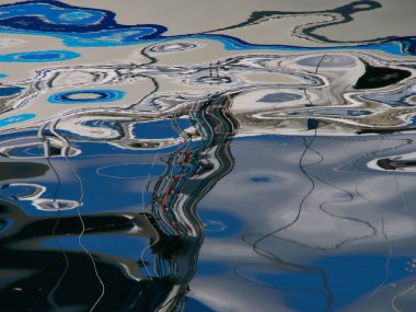 Deniz okyanusundaki soyut mavi su dalgalanmaları bir marina yelkenli sporu arka planında