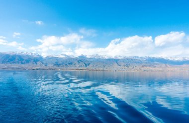 Gemideki suda ayak izleri. Mavi suda beyaz dalga. Mavi deniz suyu. Su ve gökyüzü. Gökyüzünün doğal okyanus yüzeyi. Denizde bir yaz günü manzarası.