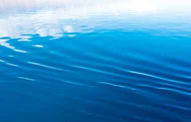 Mavi ve turuncu berrak su dokusu. Okyanusun ve denizin arkaplanı güneşle aydınlanıyor..