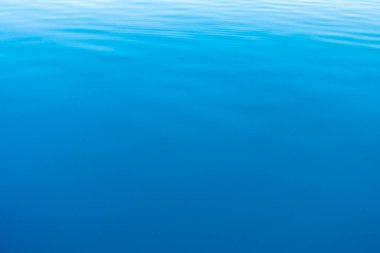 Mavi ve turuncu berrak su dokusu. Okyanusun ve denizin arkaplanı güneşle aydınlanıyor..