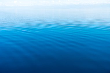 Mavi ve turuncu berrak su dokusu. Okyanusun ve denizin arkaplanı güneşle aydınlanıyor..