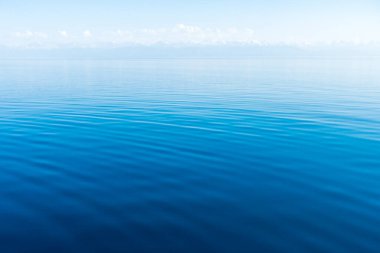 Mavi ve turuncu berrak su dokusu. Okyanusun ve denizin arkaplanı güneşle aydınlanıyor..