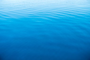 Mavi ve turuncu berrak su dokusu. Okyanusun ve denizin arkaplanı güneşle aydınlanıyor..