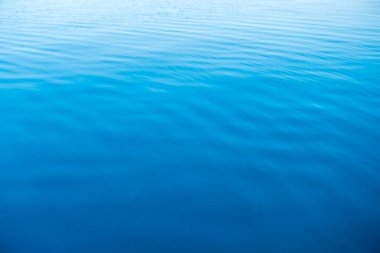 Mavi ve turuncu berrak su dokusu. Okyanusun ve denizin arkaplanı güneşle aydınlanıyor..