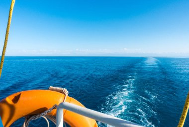 Gemi kıç tarafında, cankurtaran halatı. Teknedeki suda ayak izi. Mavi su ve ufukta dağlar. Issyk-Kul, Kırgızistan