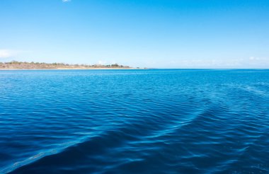 Gemideki suda ayak izleri. Mavi suda beyaz dalga. Mavi deniz suyu. Su ve gökyüzü. Gökyüzünün doğal okyanus yüzeyi. Denizde bir yaz günü manzarası.