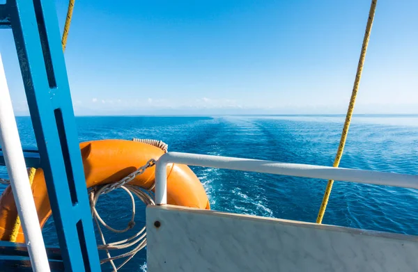 Gemi kıç tarafında, cankurtaran halatı. Teknedeki suda ayak izi. Mavi su ve ufukta dağlar. Issyk-Kul, Kırgızistan