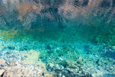 Zümrüt berrak su ve doğal taşların dokusu. Doğal arka plan. Mavi Göl. Keskin taşlar..