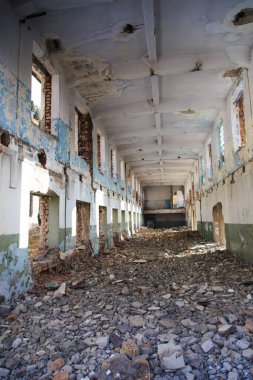 Terk edilmiş eski bir bina. Eski bir fabrikanın kalıntıları. Kirli, kirli duvarlar, büyük pencereler. Dağların ve ağaçların manzarası.