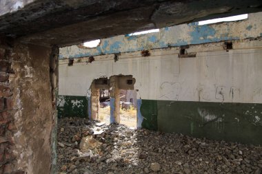 Terk edilmiş eski bir bina. Eski bir fabrikanın kalıntıları. Kirli, kirli duvarlar, büyük pencereler. Dağların ve ağaçların manzarası.