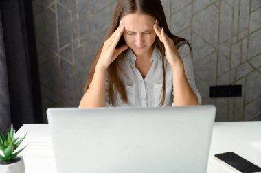 Evden uzakta bilgisayarla çalışan üzgün ve hayal kırıklığına uğramış genç Hintli kadın.