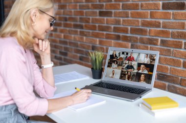 Laptop ekranında çeşitli etnik gruplardan oluşan bir kadın omzunun üzerinden geriye doğru bakış