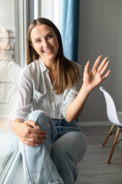 Sevecen, tapılası genç bir kadın kameraya el sallıyor.