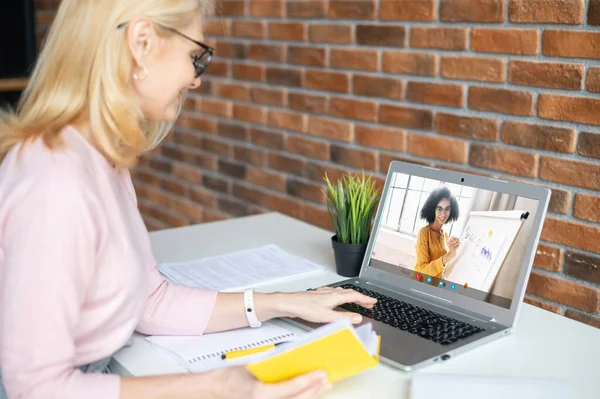 Дві жінки-колеги розмовляють онлайн через відеоз'єднання на ноутбуці — стокове фото