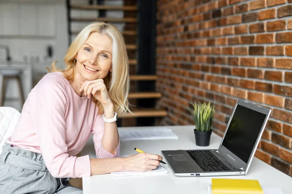 Charmante femme d'affaires blonde mature positive dans des lunettes assise au bureau — Photo