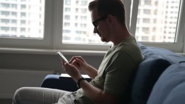 Gülümseyen adam günlük kıyafet mesajları takıyor, akıllı telefondan mesaj atıyor.