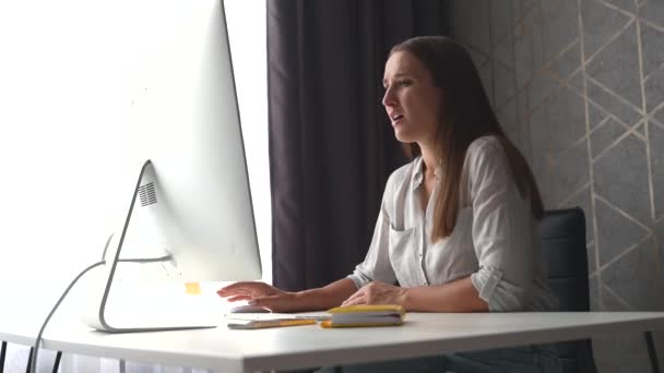 Empörte junge Frau sitzt am Schreibtisch vor dem PC — Stockvideo