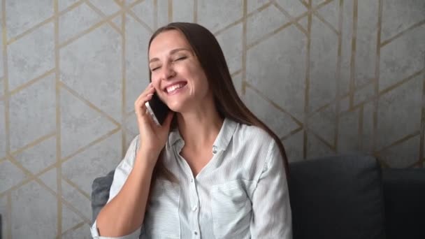 Close-up portret van lachende jonge vrouw praten met de smartphone en kijkt weg — Stockvideo