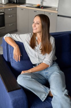 Kaygısız sakin kadın kanepede oturuyor ve rahat bir atmosferde rüya görüyor.