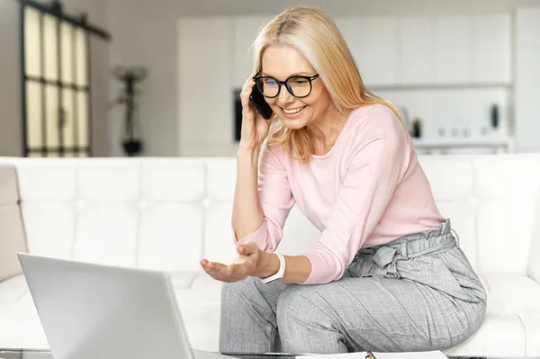 Portrait d'une charmante femme blonde mature d'âge moyen portant des lunettes à l'aide d'un smartphone — Photo