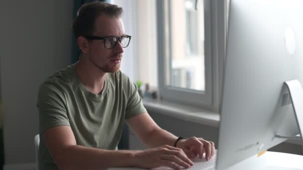 Inteligentní mladý muž se stylovými brýlemi pracující vzdáleně z domova — Stock video