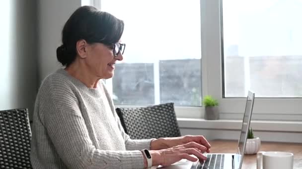 Senior kvinnlig entreprenör som använder en bärbar dator för distansarbete — Stockvideo