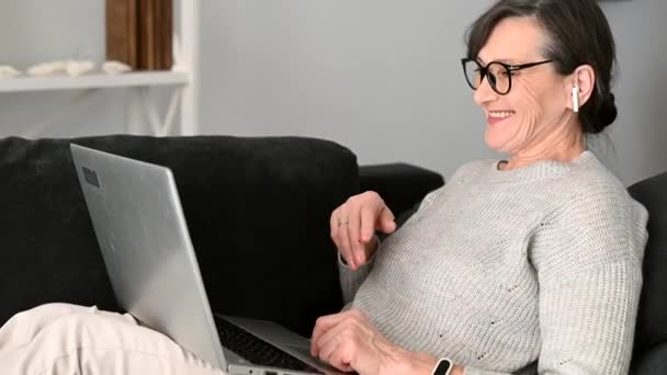 Senior kvinna som använder bärbar dator hemma för videosamtal, arbetar på distans — Stockvideo