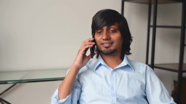 Усміхнений індійський бізнесмен у розумній повсякденній сорочці розмовляє на смартфоні — стокове відео