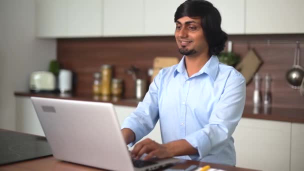 Sonriente optimista joven indio con camisa casual usando portátil — Vídeo de stock