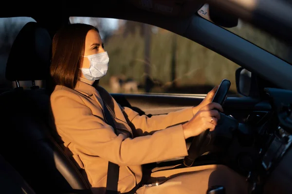 Молода жінка в розумній випадковості в захисній медичній масці за кермом автомобіля — стокове фото
