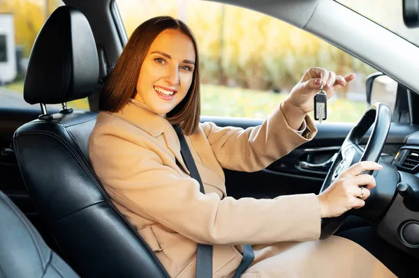 Молодая женщина показывает ключ от нового современного автомобиля — стоковое фото