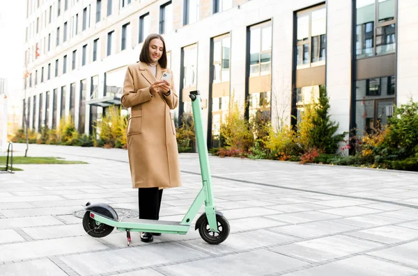 Felice donna d'affari cavalcando in smart casual abbigliamento equitazione in ufficio su un e-scooter — Foto Stock
