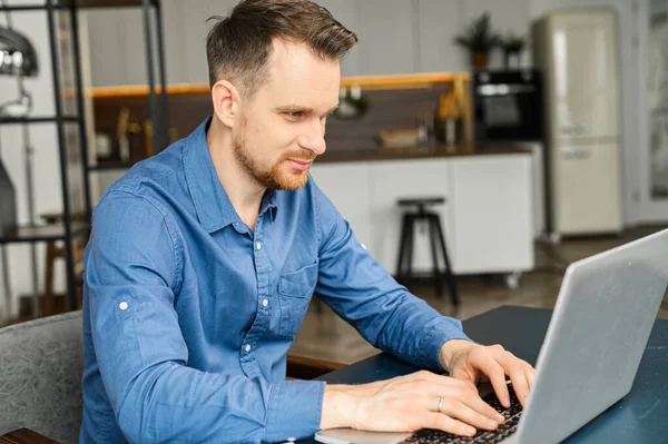 Freelancer masculino inteligente sério usando laptop para trabalho on-line sentado na mesa — Fotografia de Stock