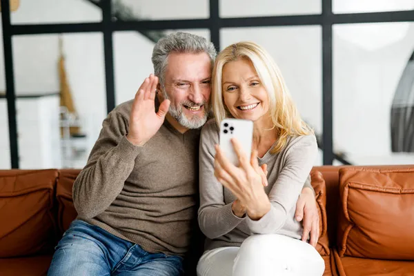 Medelålders par tar selfie med en smartphone eller ringer videosamtal — Stockfoto