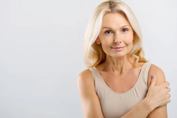 Good-looking beautiful middle-aged woman posing in studio over grey — Stock Photo, Image