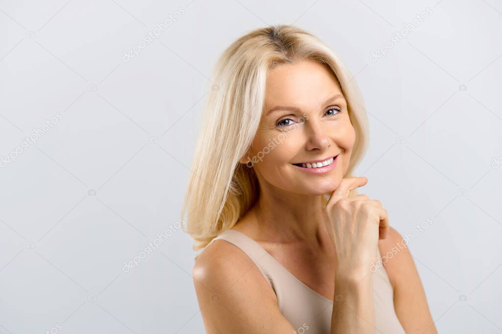 Woman isolated on grey background looking at the camera and smiles toothy