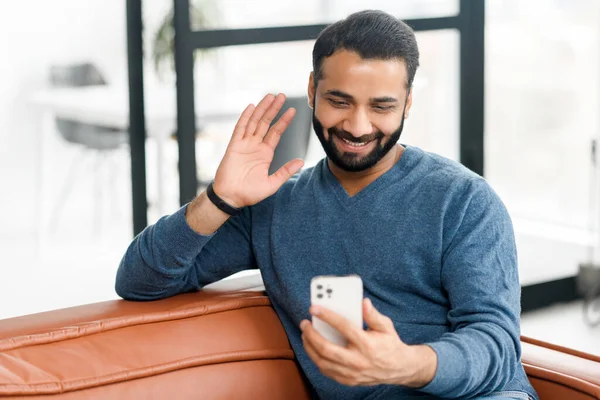 Šťastný indiánský muž drží mobilní telefon a mává ahoj — Stock fotografie