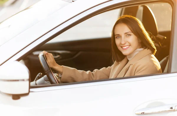 A young woman in coat is driving a car — Stock Photo, Image