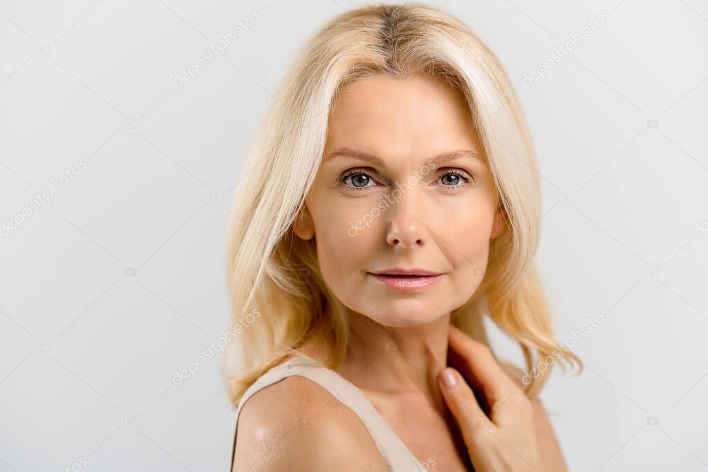 Headshot beautiful middle-aged blonde woman with fresh clean healthy skin isolated on grey