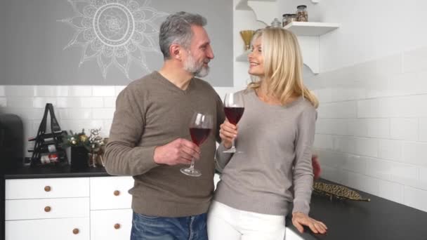 Happy middle-aged wife and husband holding glasses of wine and hugging at home — Stock Video