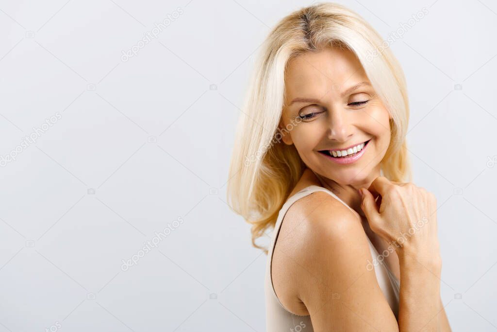Well-looking middle-aged lady laughing playfully, hand near face