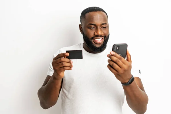 アフリカ系アメリカ人の男がクレジットカードとスマートフォンを持っている — ストック写真