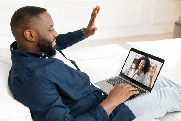 Ein multiethnischer Typ benutzt Laptop für Videoanrufe, legt sich auf die Couch und unterhält sich entspannt — Stockfoto