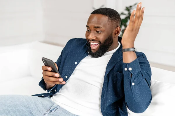 Glad förvånad svart kille stirrar på smartphone skärmen, läsa goda nyheter — Stockfoto