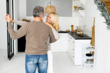 Neşeli orta yaşlı çift evdeki mutfakta eğleniyor.