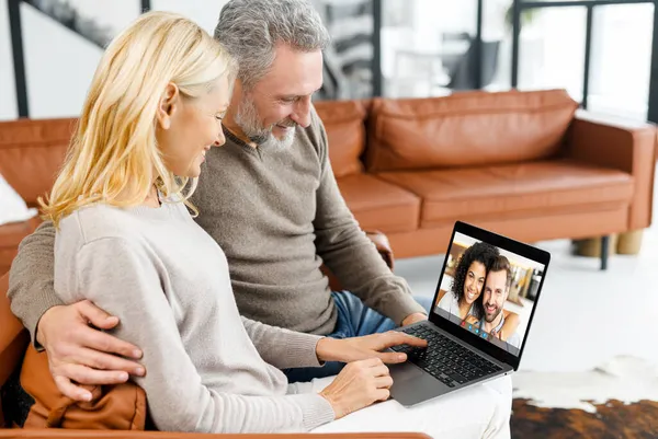 Casal de meia-idade usando laptop para conexão de vídeo com crianças adultas — Fotografia de Stock