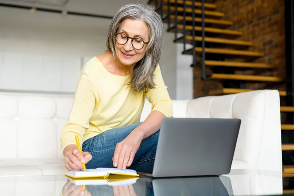 Зріла зосереджена жінка дивиться онлайн вебінари на ноутбуці — стокове фото